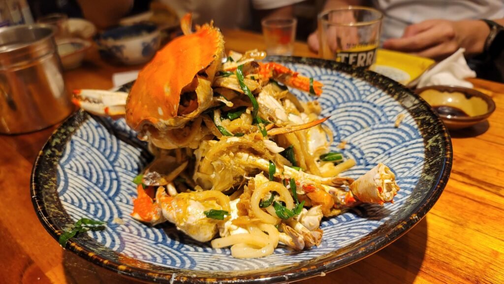 A detailed close-up of a delicious Jeju chili crab and noodle dish served in a blue and white patterned bowl during a Jeju Island travel food tour.
