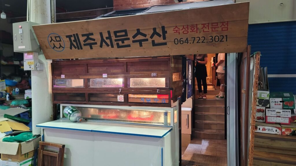 The wooden sign and entrance of the local restaurant 'Jeju Seomun Susan', a hidden gem known for fresh seafood on Jeju Island travel.