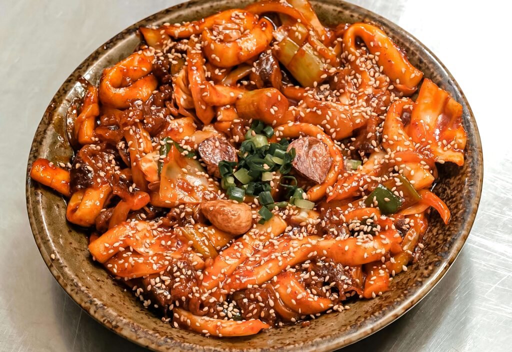 A close-up shot of spicy rice cakes (Tteokbokki) representing the vibrant food culture in South Korea Travel Trends 2026.