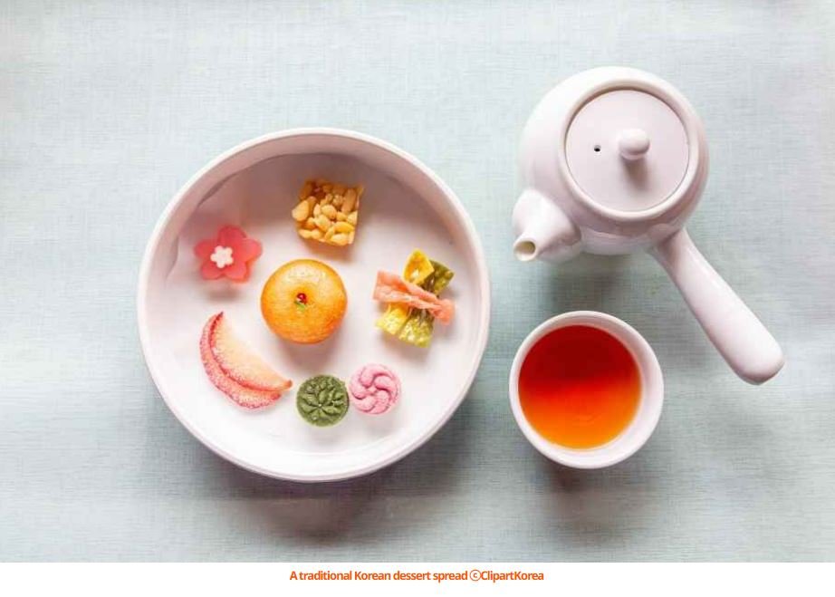 A beautiful spread of the best Korean desserts, including traditional Yakgwa and modern pastries on a wooden table