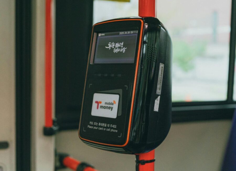 A close-up of tapping a T-money card on a bus terminal, a crucial rule in the Korea public transport transfer guide